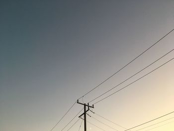 Low angle view of silhouette electricity pylon against sky