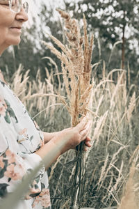 Midsection of woman holding corn field