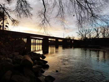 Bridge over river against sky at sunset