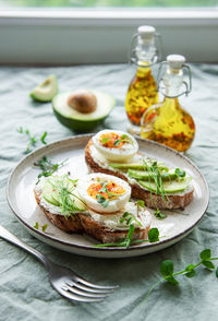 Bread toast, boiled eggs, avocado slice, microgreens on a plate, breakfast time