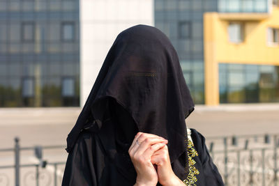 Portrait of a muslim woman in national clothes covering her face in a european city.