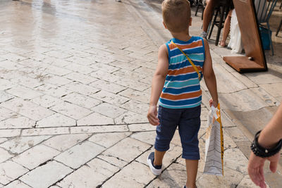 Rear view of boy walking on footpath