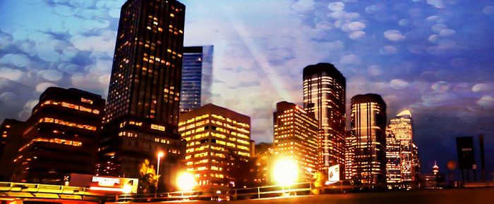 Low angle view of modern buildings against cloudy sky