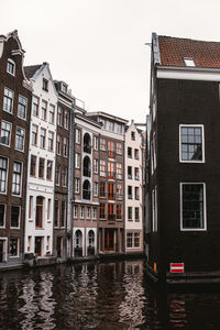 Buildings by canal against sky