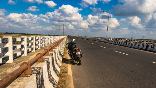 Man riding motorcycle on road against sky