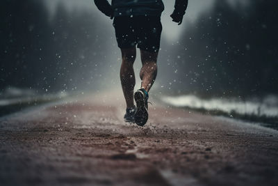 Low section of man running on snow