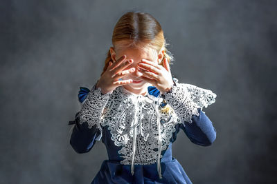 Young woman drinking water while standing against black background