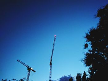 Low angle view of crane against clear blue sky