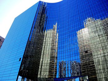 Low angle view of skyscrapers against blue sky