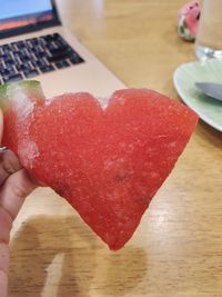 Midsection of person holding heart shape on table