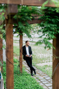 Full length portrait of young woman against trees
