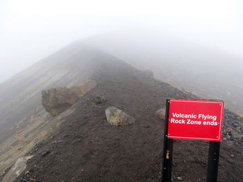 Information sign on mountain against sky