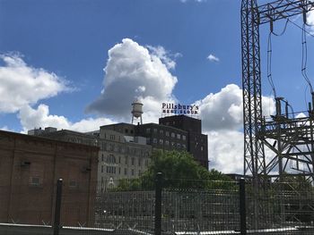 Low angle view of crane by building against sky