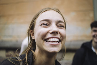 Happy teenage girl laughing with friends at street