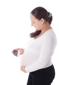 Woman looking away while standing against white background