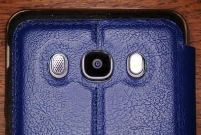 Cropped image of mobile phone with blue cover on wooden table