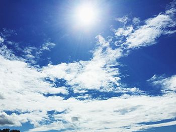 Low angle view of sun shining through clouds