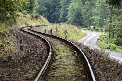 Railway curve and asphalt winding road in a forest. two communication and transport routes.