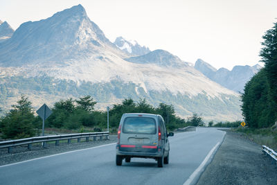 Car on road by mountains against sky