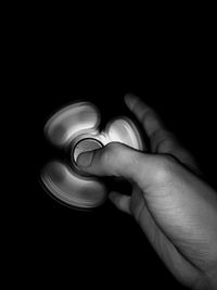 Close-up of hand holding candle against black background