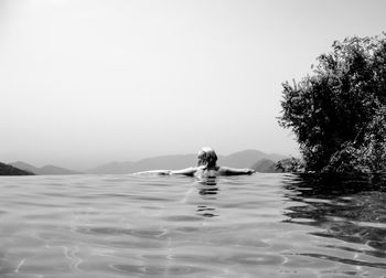 Man swimming in sea against clear sky