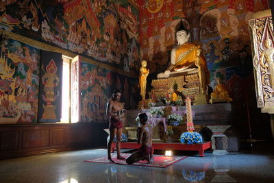Shirtless men praying in buddhist temple
