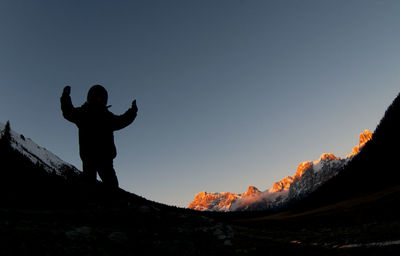 Rear view of man standing on mountain against clear sky