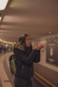 Young woman standing against illuminated city in background