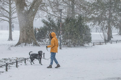 The young woman and the dog playing outside in the snow flurry