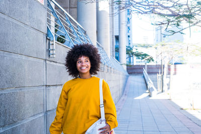 Smiling young woman standing on footpath