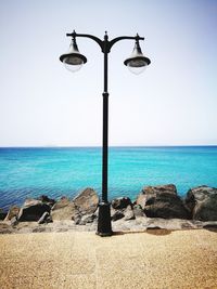 Street light by sea against clear sky