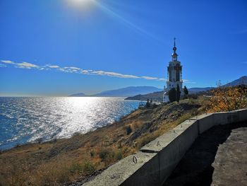 Lighthouse by sea against sky