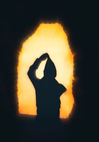 Silhouette woman standing against orange sky