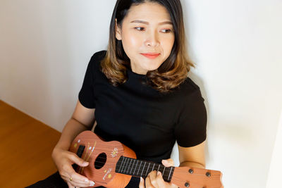 Portrait of a young woman playing guitar