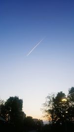 Low angle view of silhouette trees against blue sky