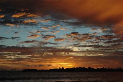 Scenic view of sea against dramatic sky during sunset