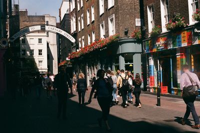 People walking on street amidst buildings in city