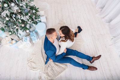 Couple sitting against christmas tree at home
