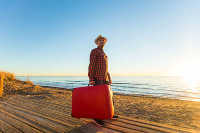 Man wearing hat on beach against clear sky