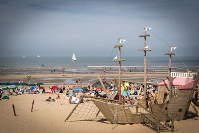 People at beach against cloudy sky