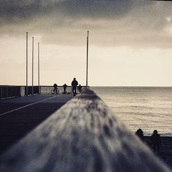 Pier on sea against cloudy sky