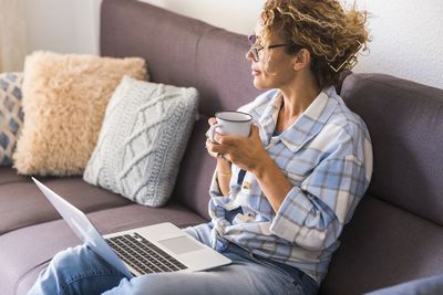 Midsection of man using mobile phone while sitting on sofa at home