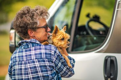 Senior woman holding dog outdoors