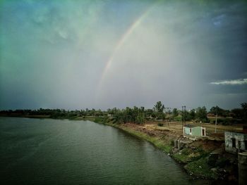 Scenic view of rainbow over river against sky