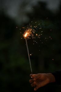 Cropped hand holding sparkler at night