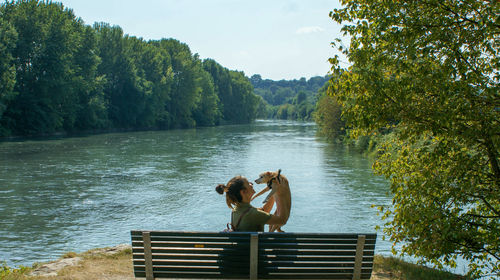 Man sitting by lake against trees