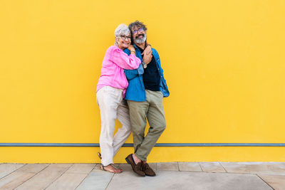 Side view of woman standing against yellow wall