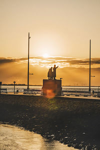 Silhouette people standing on beach against sky during sunset