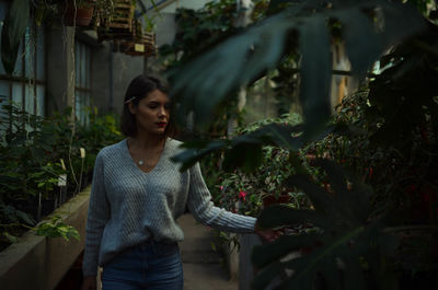 Young woman standing by plants