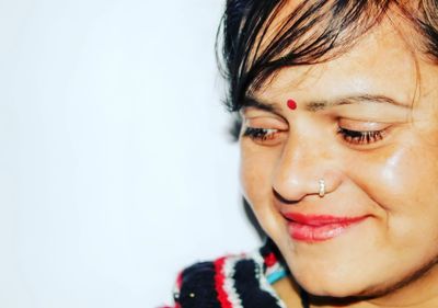 Close-up of shy smiling woman looking away against wall